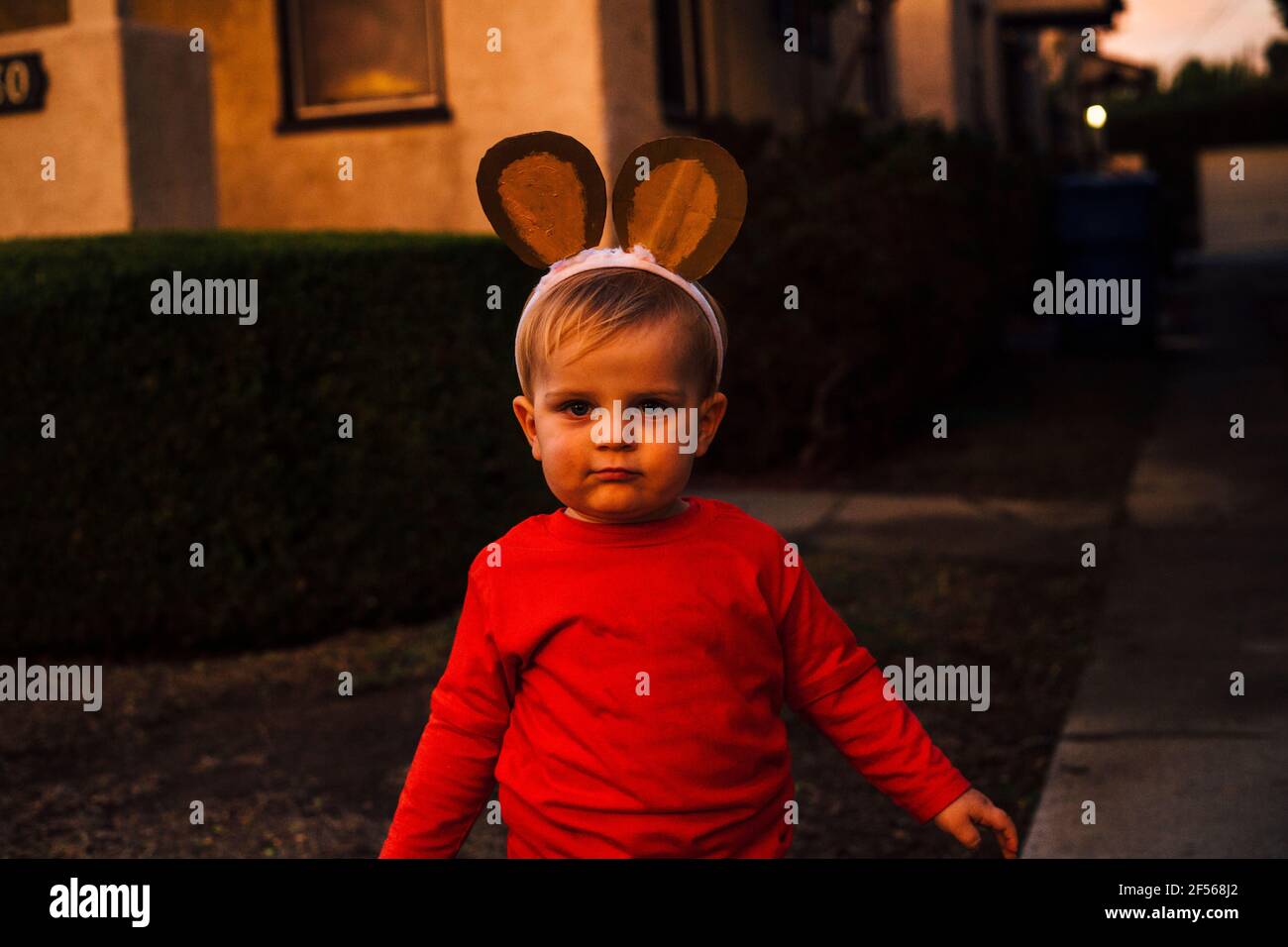 Portrait of cute little boy wearing monkey ears headband standing outdoors at dusk Stock Photo