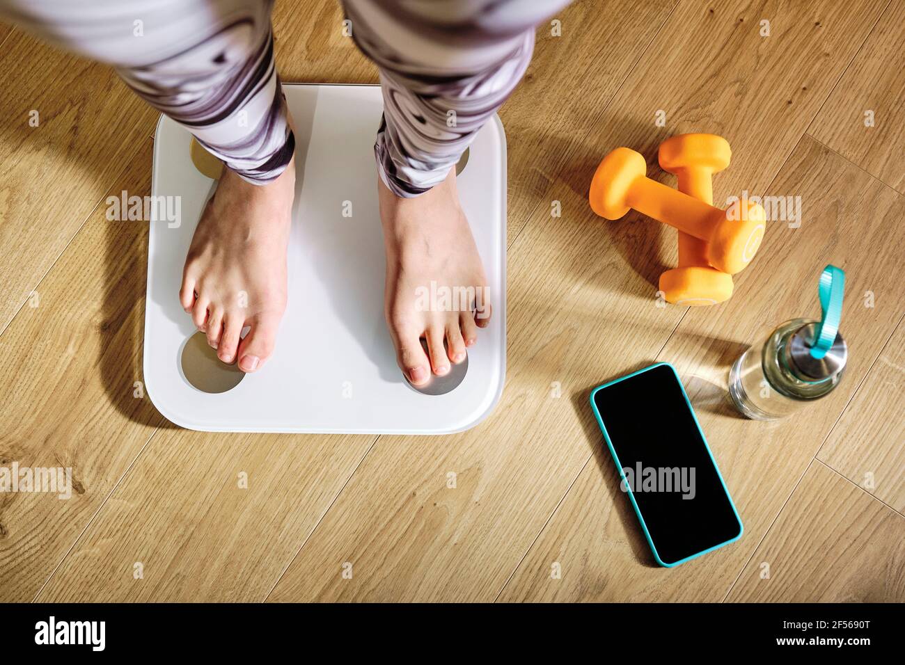 A woman standing on a weight scale Stock Photo - Alamy