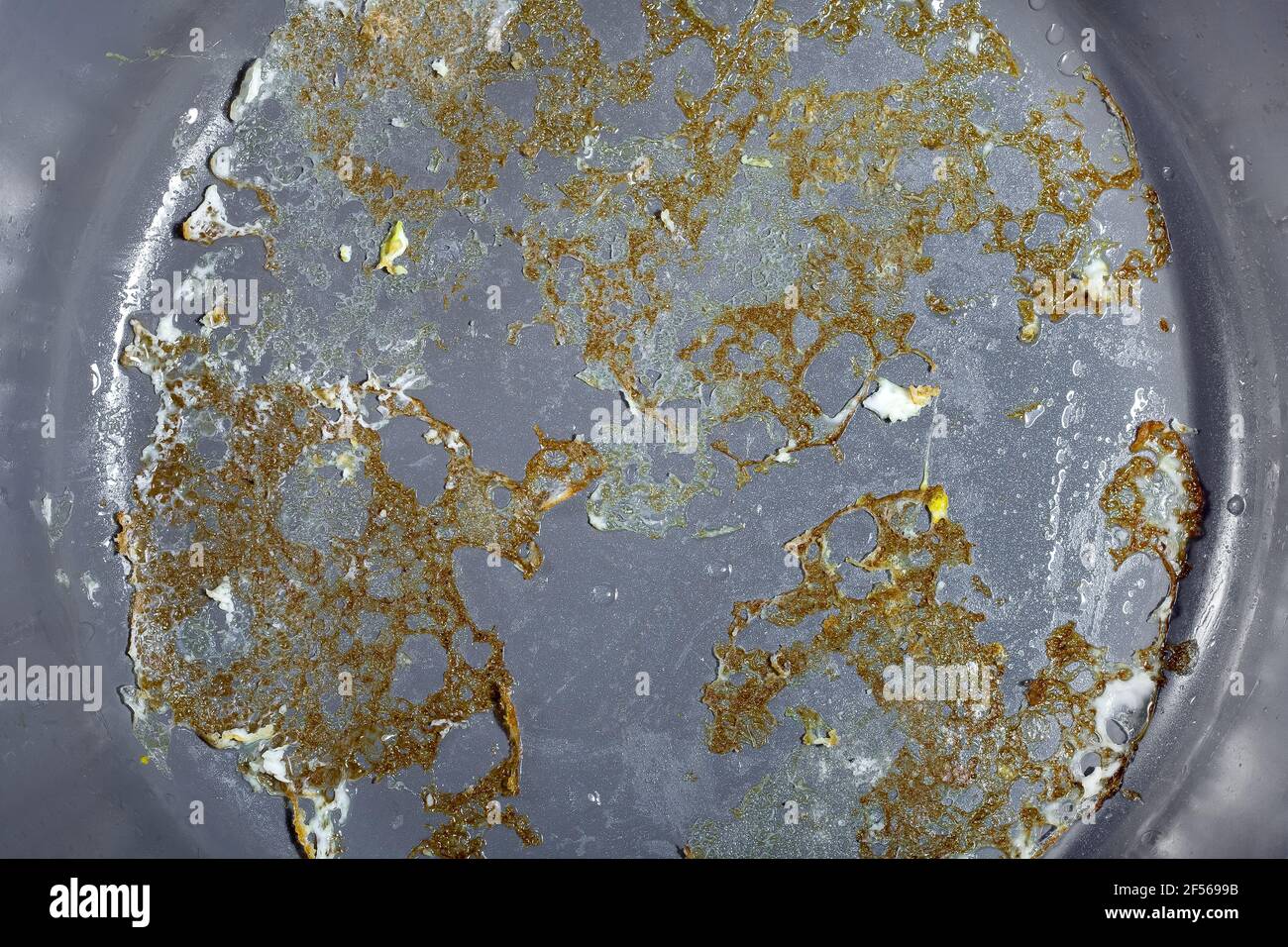 gray non-stick surface of a frying pan with burnt fried eggs close-up, kitchen utensils for cooking fried foods, nobody. Stock Photo