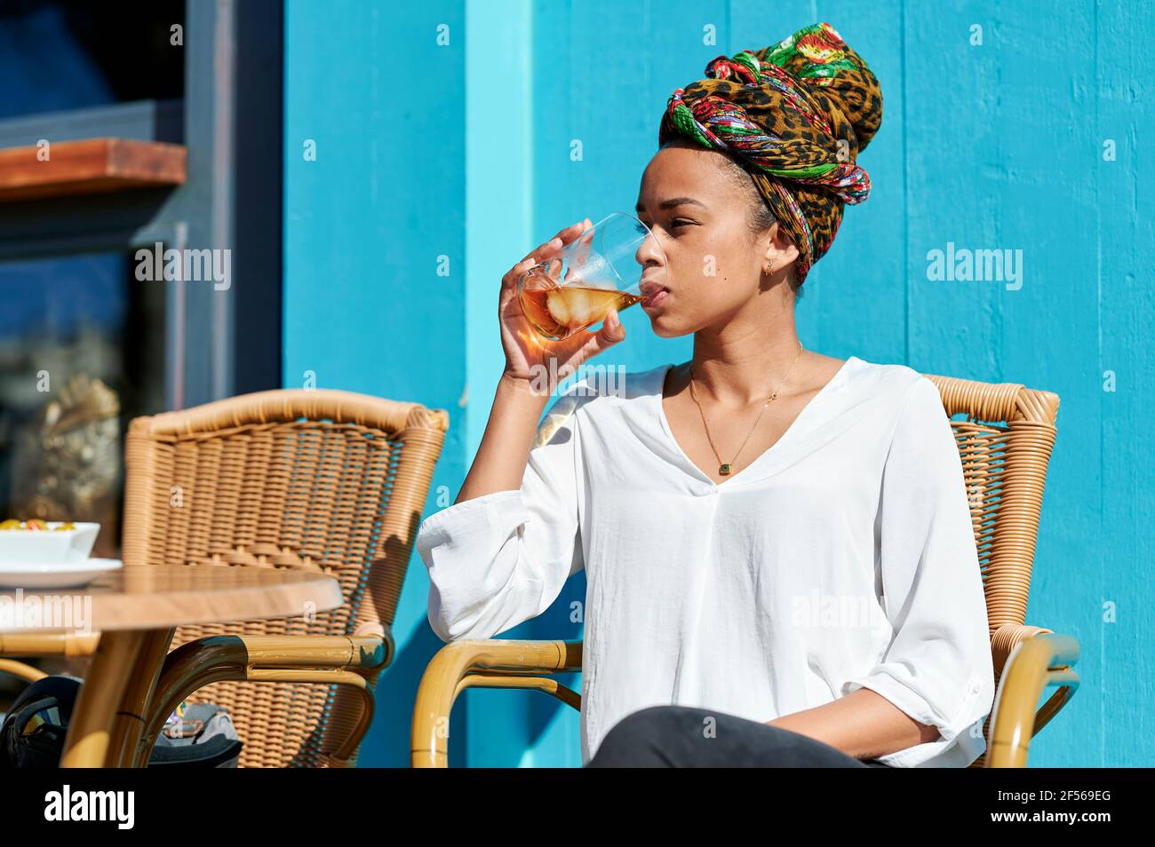 Woman wearing headscarf drinking alcohol while sitting at bar Stock Photo