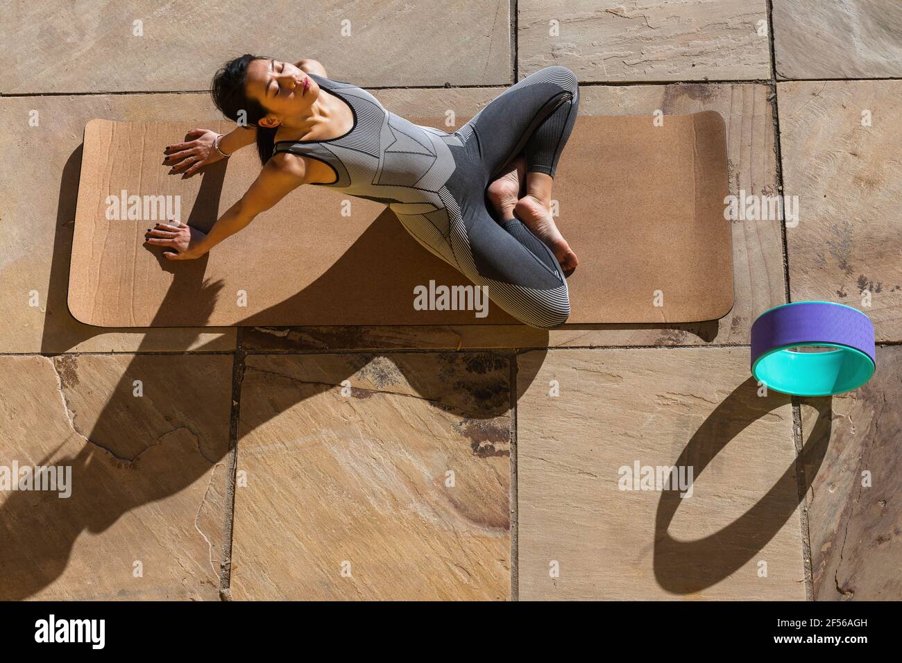 Sportswoman doing relaxation exercise on mat at promenade Stock Photo