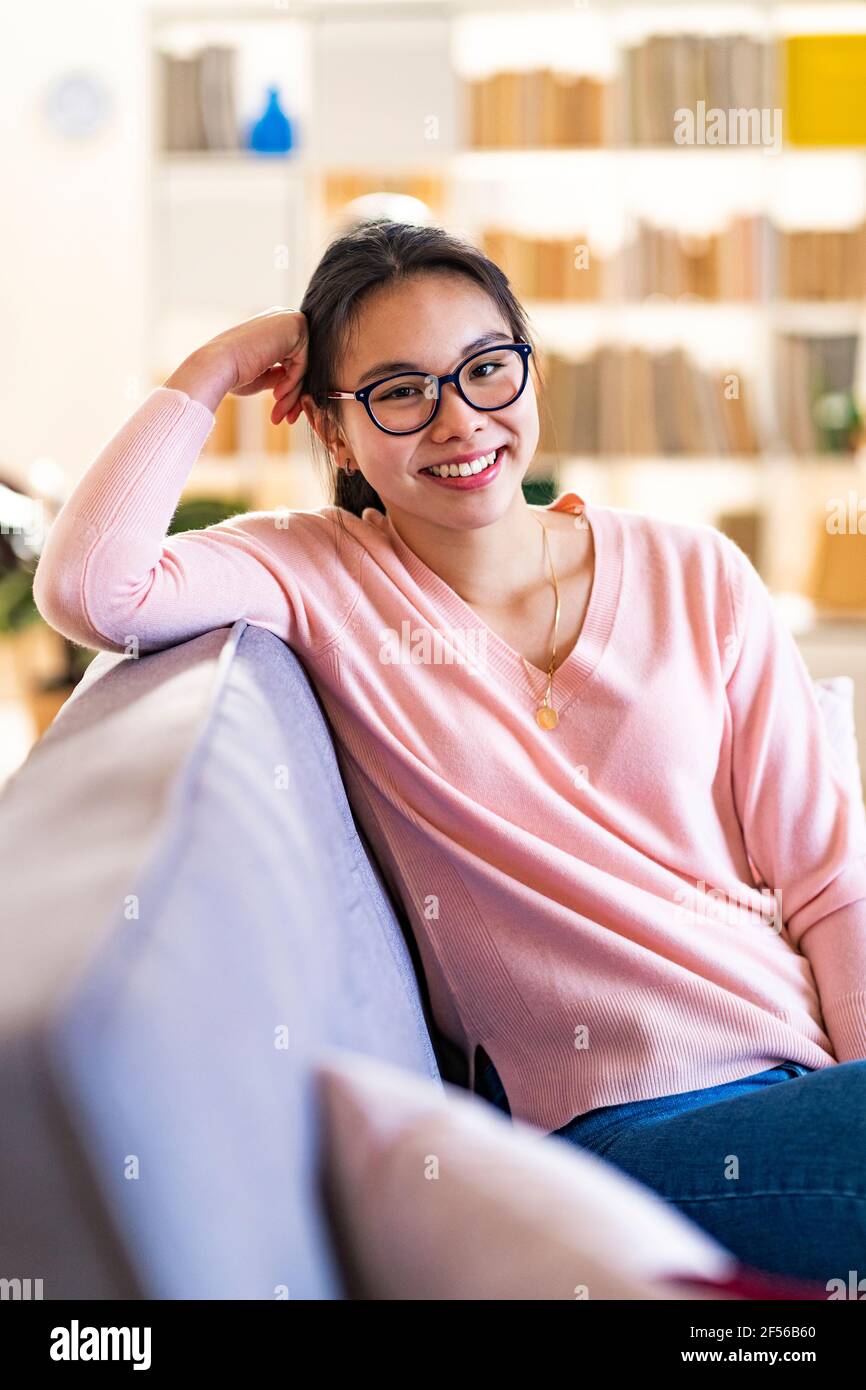 Smiling woman sitting on sofa at home Stock Photo