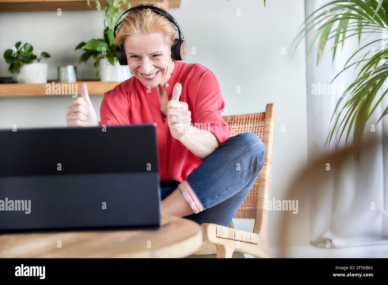 Happy mature woman showing thumbs up gesture during video call on ...