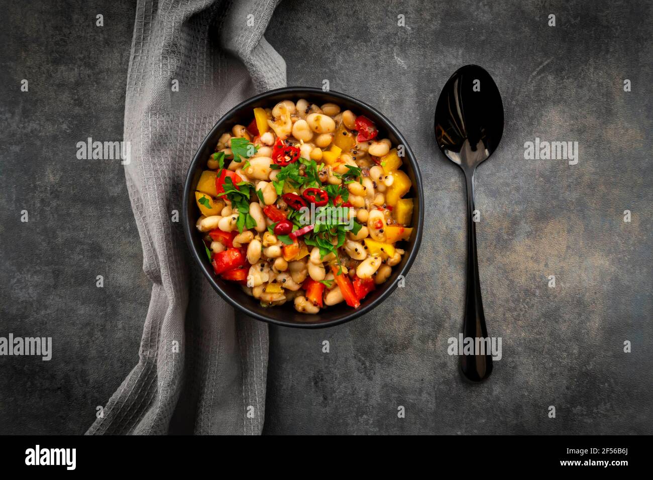 Studio shot of bowl of bean stew with bell and chili peppers, quinoa and parsley Stock Photo
