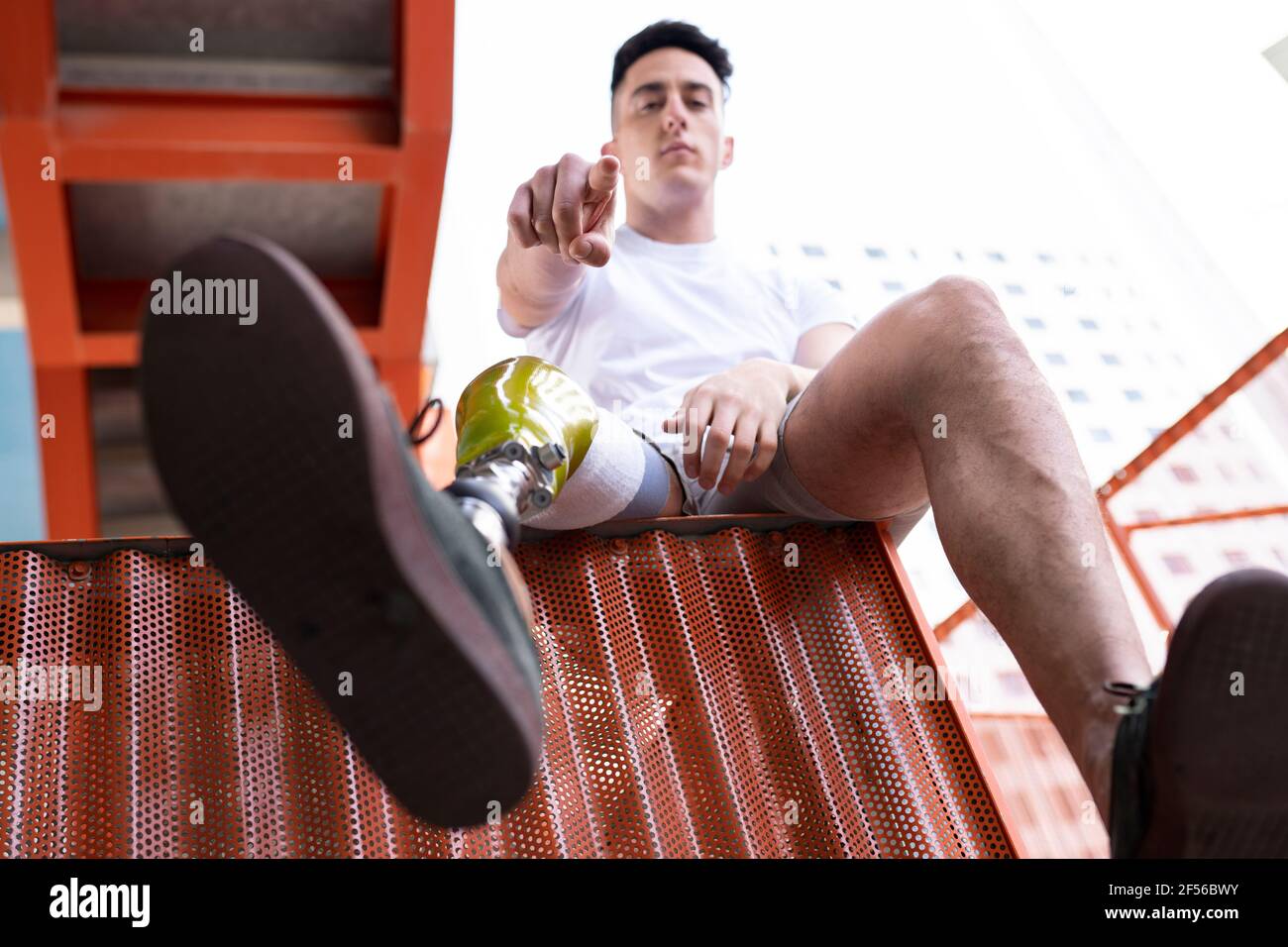 Amputated young man pointing while sitting on metal Stock Photo