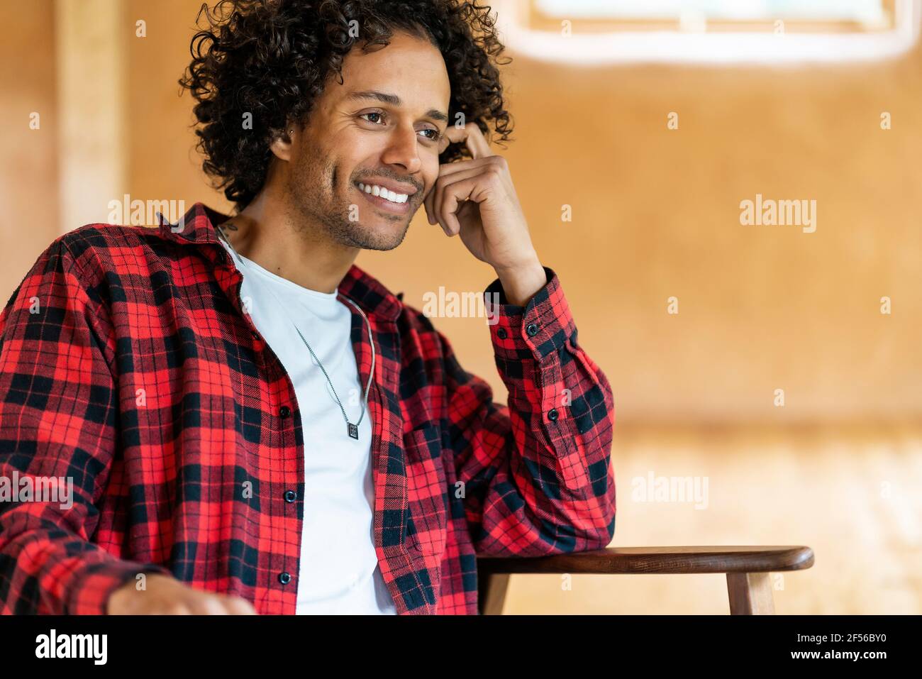 Smiling man looking away while sitting at spacious room Stock Photo