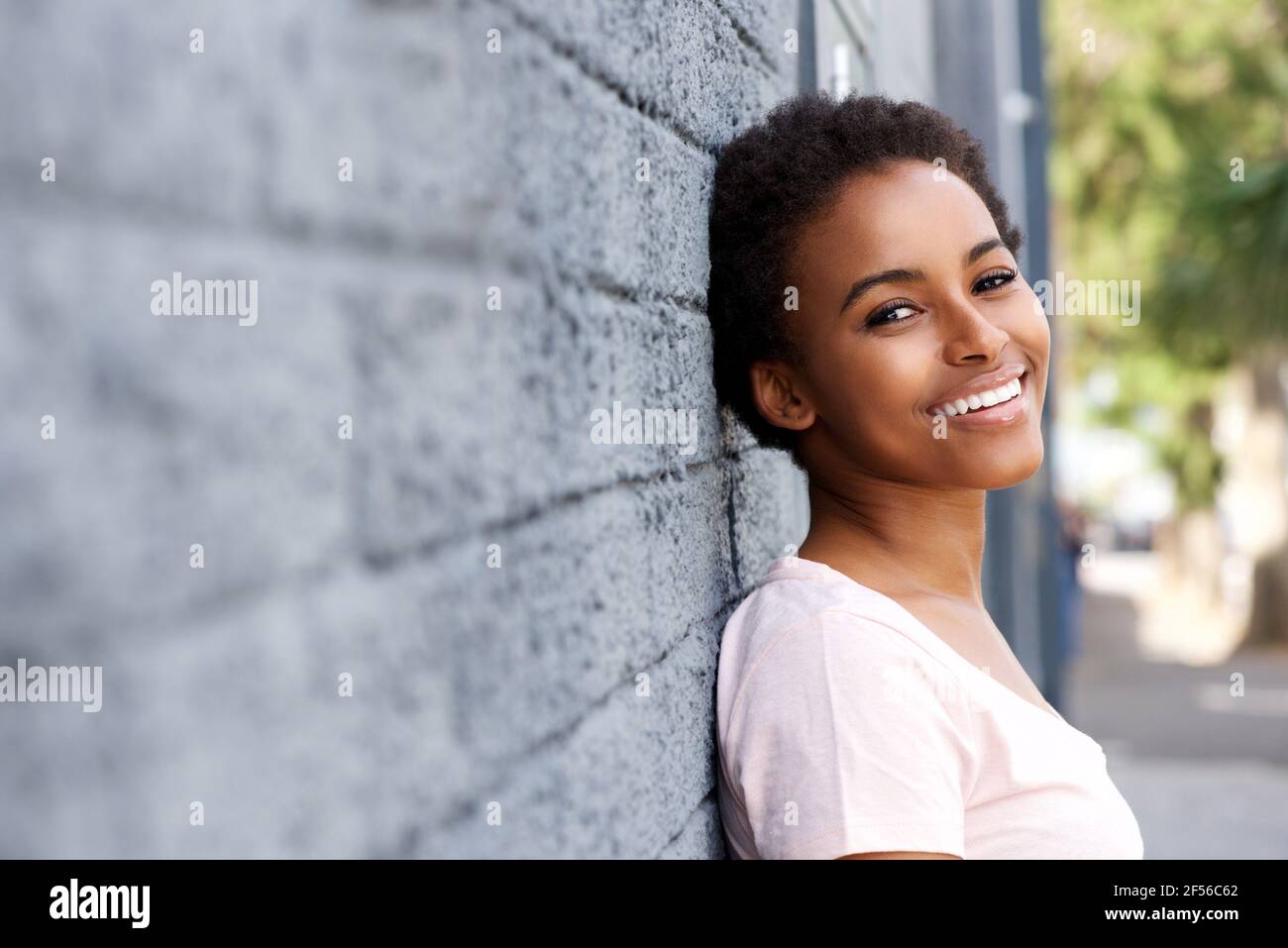 Close up portrait of smiling black girl leaning against wall Stock ...