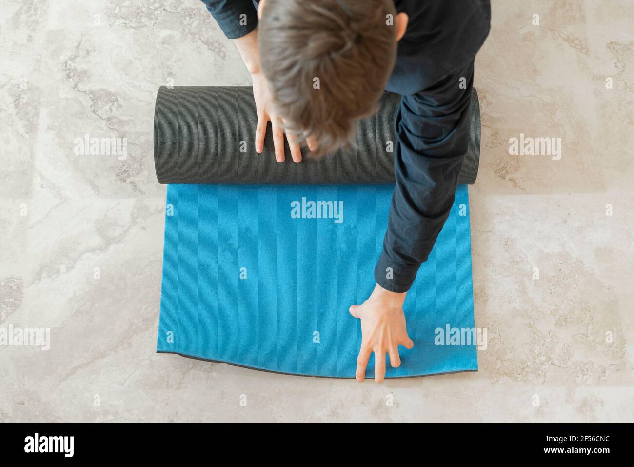 a man rolling the yoga mat on the floor in yoga class workout Stock