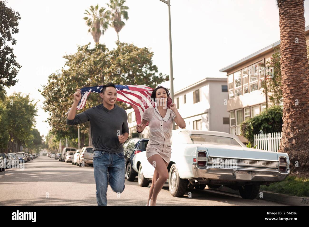Young male and female running with American flag on street Stock Photo