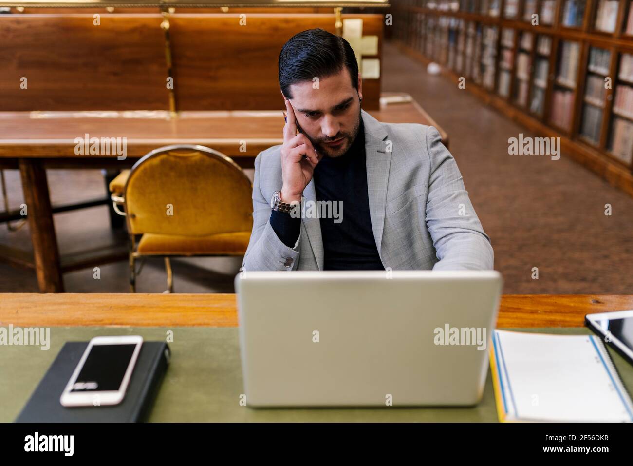 Businessman working on laptop while sitting in library Stock Photo