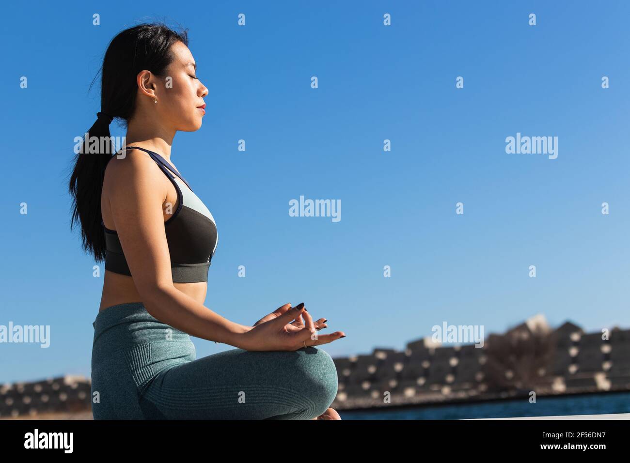 Young female athlete meditating while practicing lotus position on sunny day Stock Photo