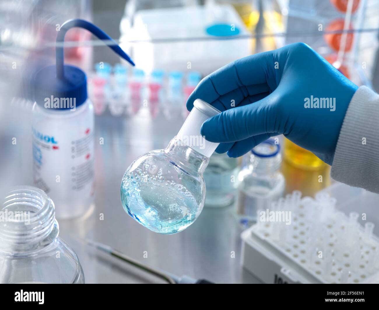 Scientist holding flask containing chemical formula under fume hood in laboratory Stock Photo