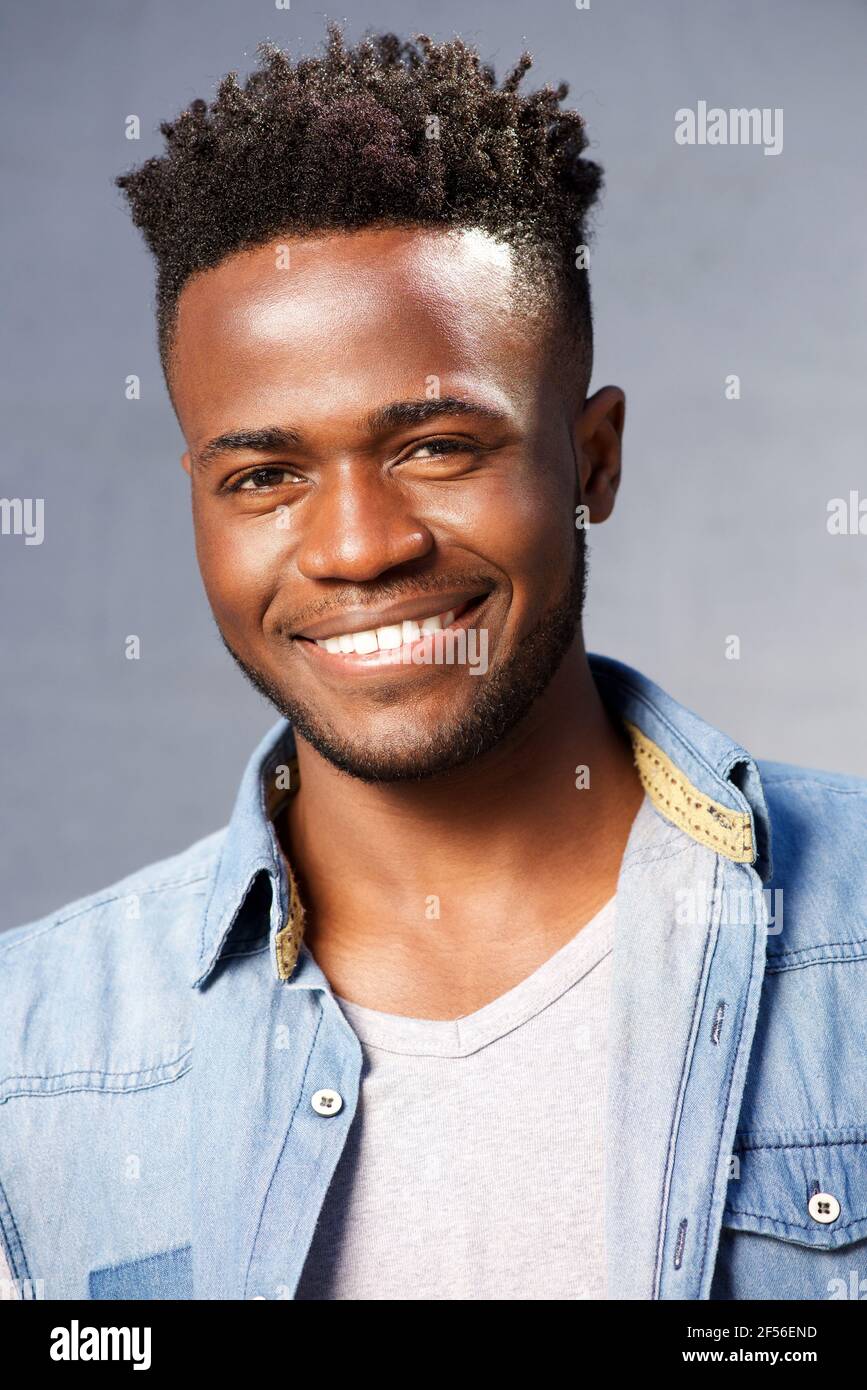 Close portrait of handsome smiling black man standing by gray ...