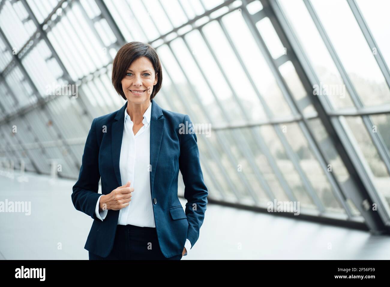 Confident female professional standing in corridor Stock Photo