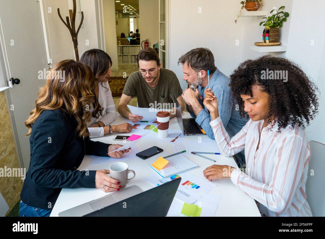 Multi-ethnic coworkers discussing while sitting at desk in office Stock Photo
