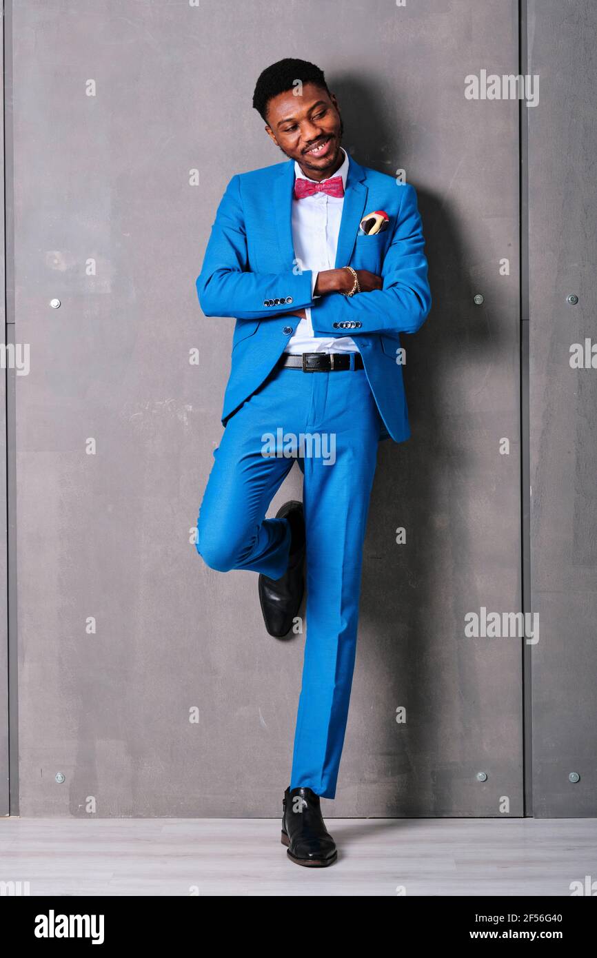 Smiling man in suit with arms crossed while standing against wall Stock Photo Alamy