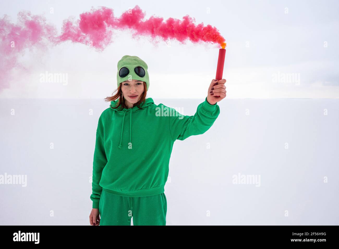 Woman holding red smoke distress flare against sky Stock Photo