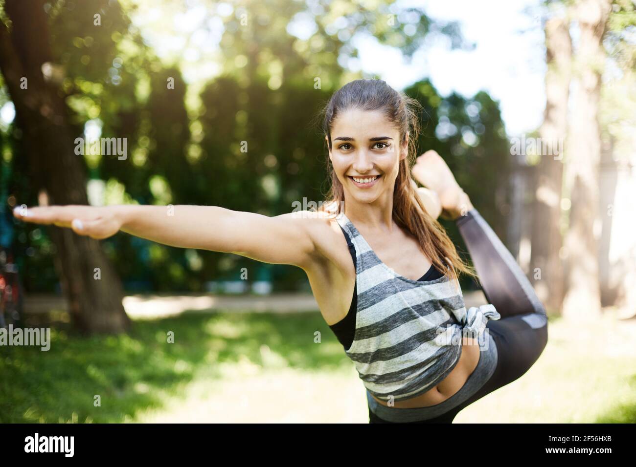 Girl practicing bikram yoga boses standing on one leg. Tuladandasana asana. Stock Photo