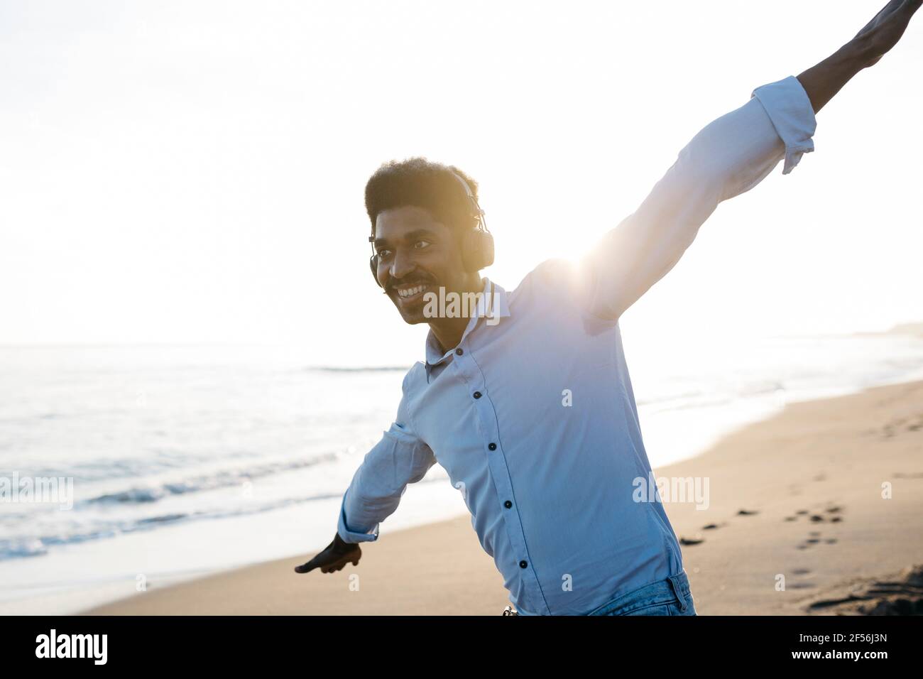 Smiling man enjoying at beach while imitating airplane Stock Photo