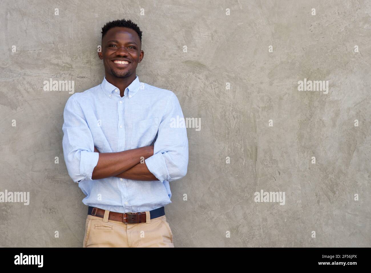 Portrait of handsome young african man smiling with arms crossed by ...