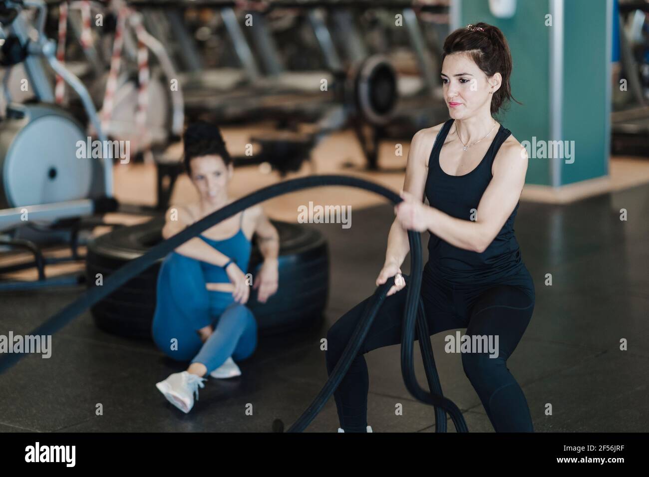 Female sportsperson exercising with rope during strength training in gym Stock Photo