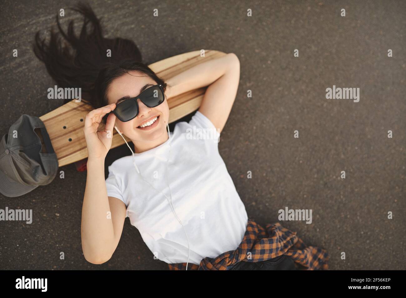 Overhead shot carefree teenage girl lying on concrete at skatepark wear ...