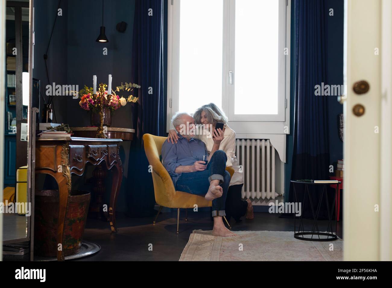 Smiling senior couple using mobile phone while sitting at home Stock Photo