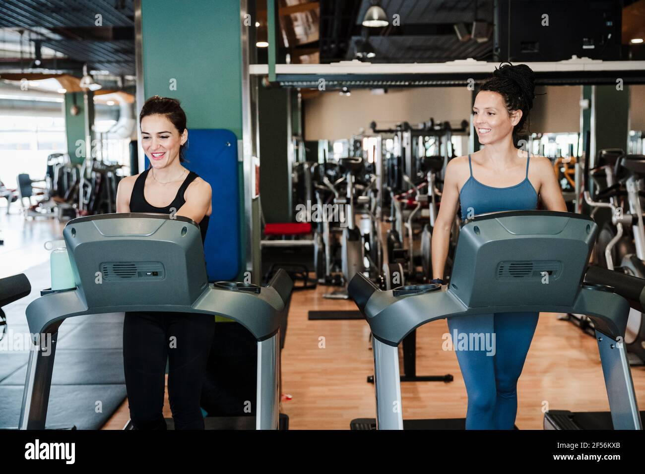 Smiling female athletes exercising on treadmill in health club Stock Photo