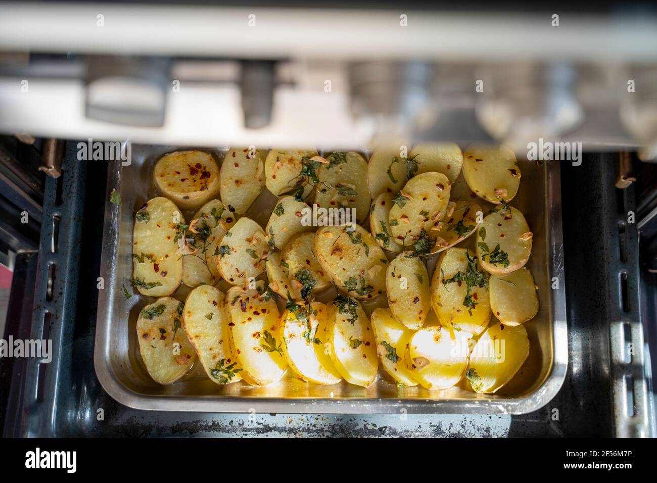 Oven roasted potatoes with garnished coriander in oven tray Stock Photo