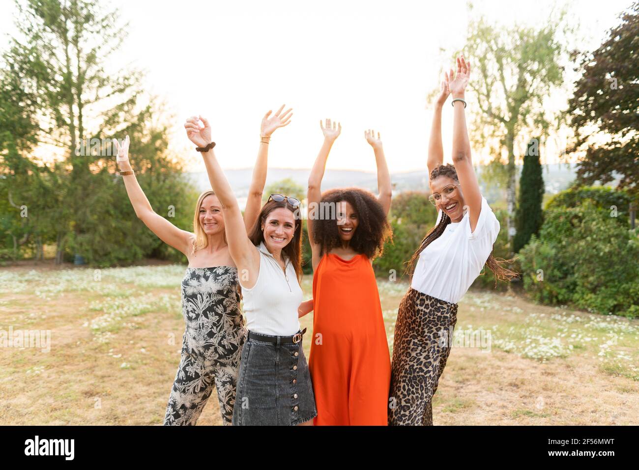 Cheerful female friends with hands raised at park Stock Photo