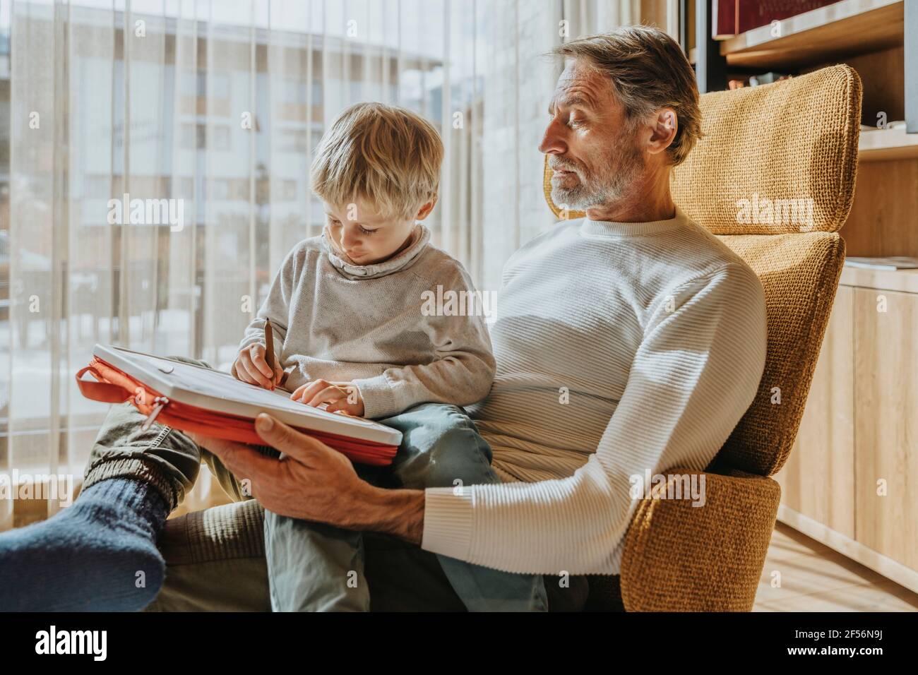 Boy drawing while sitting on father's lap Stock Photo Alamy