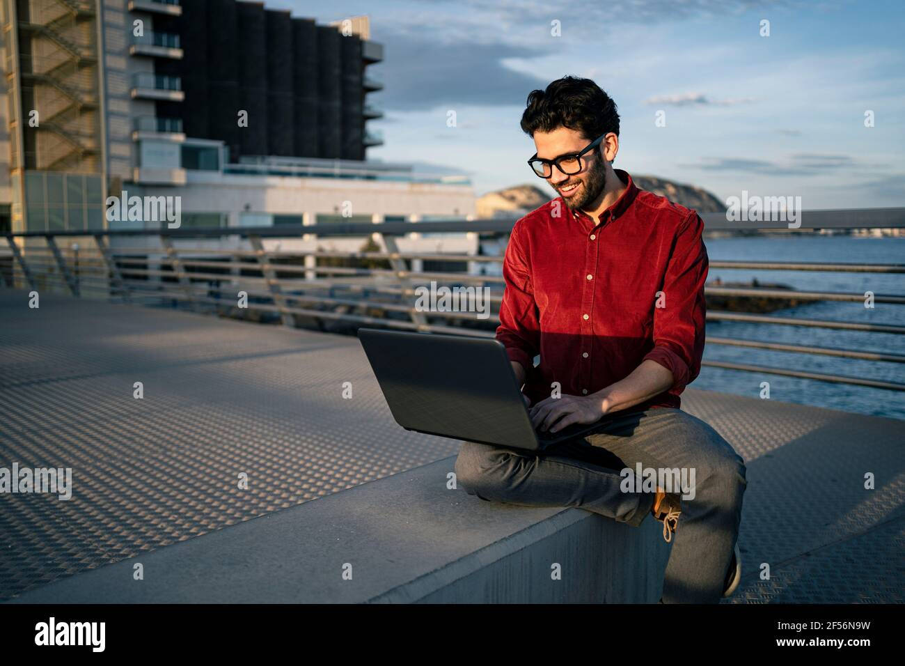 Smiling male freelance worker using laptop on bench Stock Photo