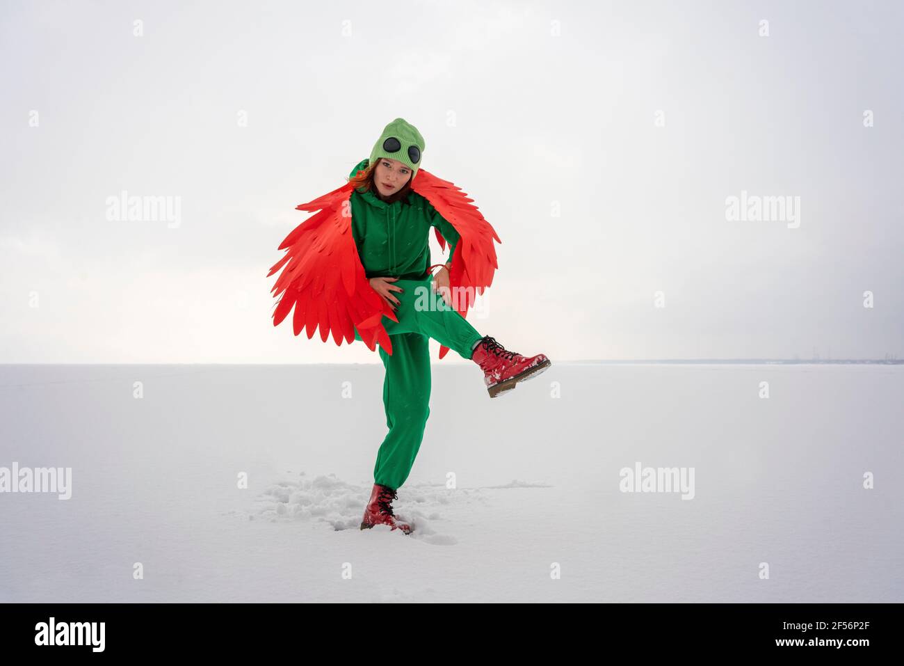 Woman in bird costume holding knee against sky Stock Photo