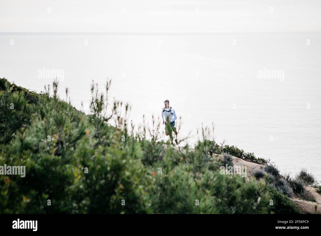 Man running up on mountain by sea Stock Photo