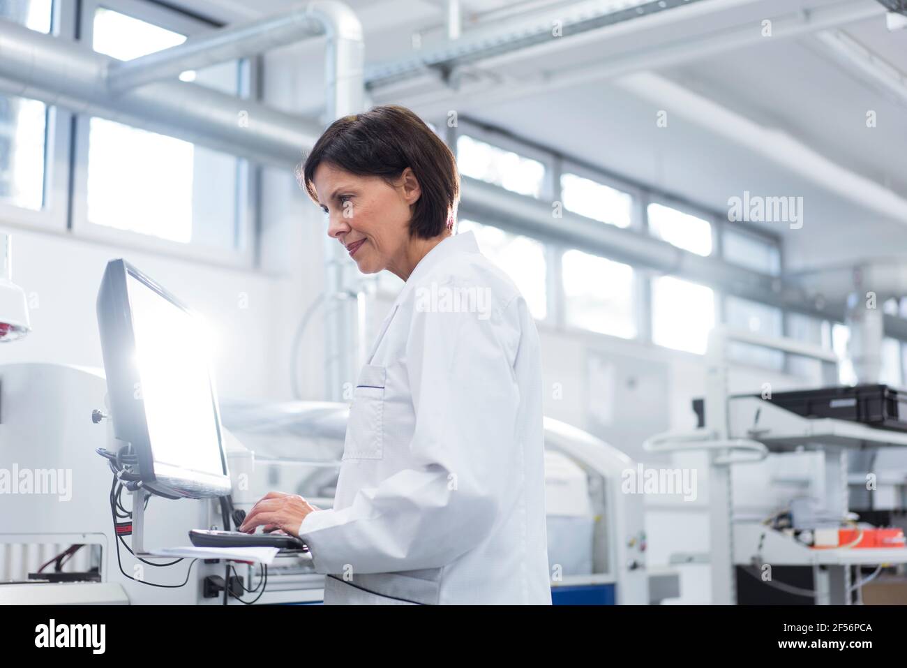 Female technician working on computer at factory Stock Photo
