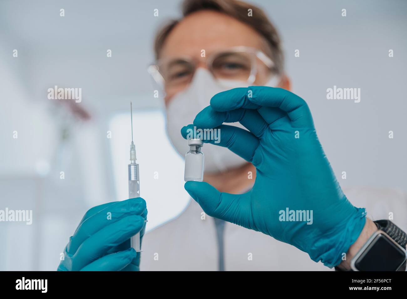 Healthcare worker holding COVID-19 vaccination vial and syringe at examination room Stock Photo