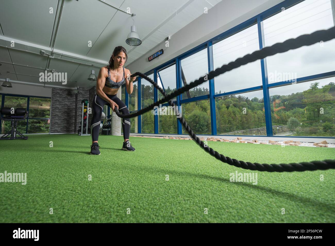 Determinant female athlete exercising with rope at health club Stock Photo