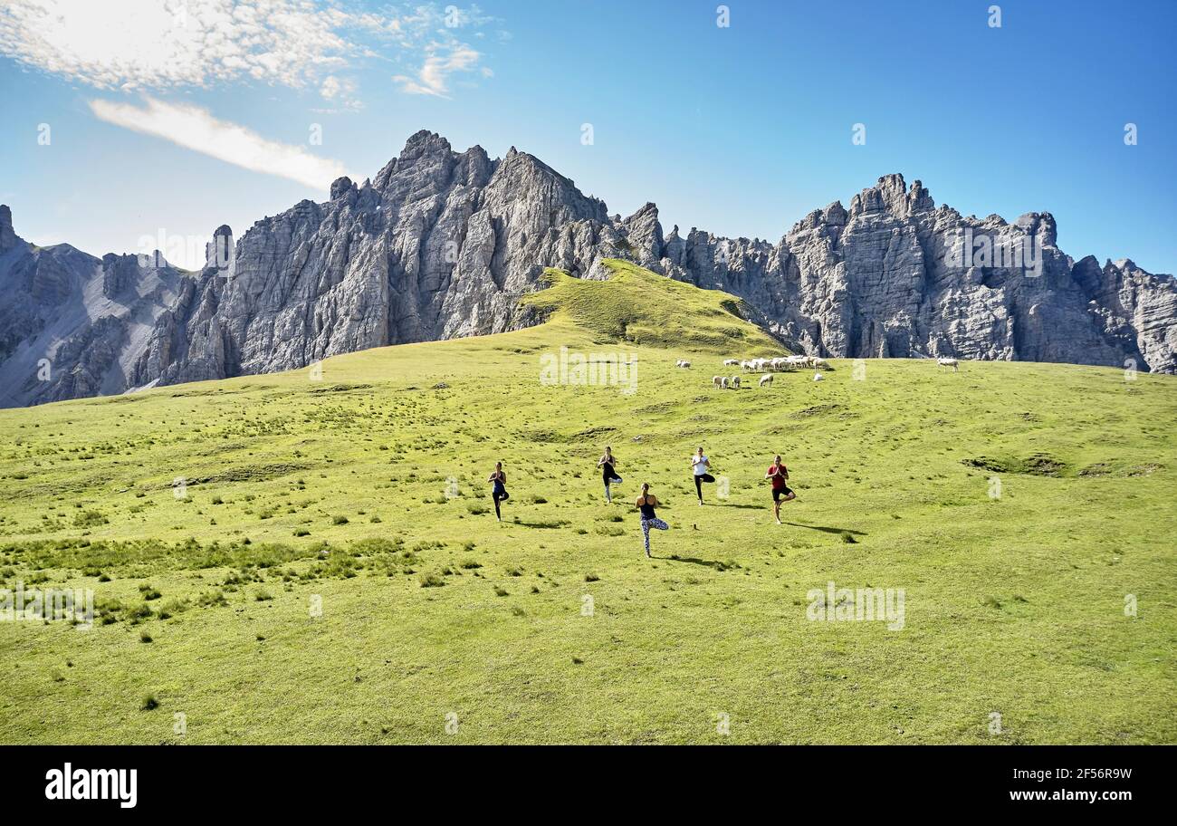 Multi-ethnic man and women practicing yoga against mountain Stock Photo