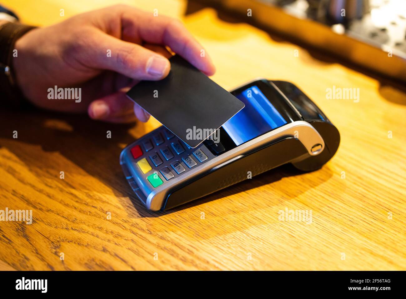 Man paying with credit card through reader machine at cafe Stock Photo