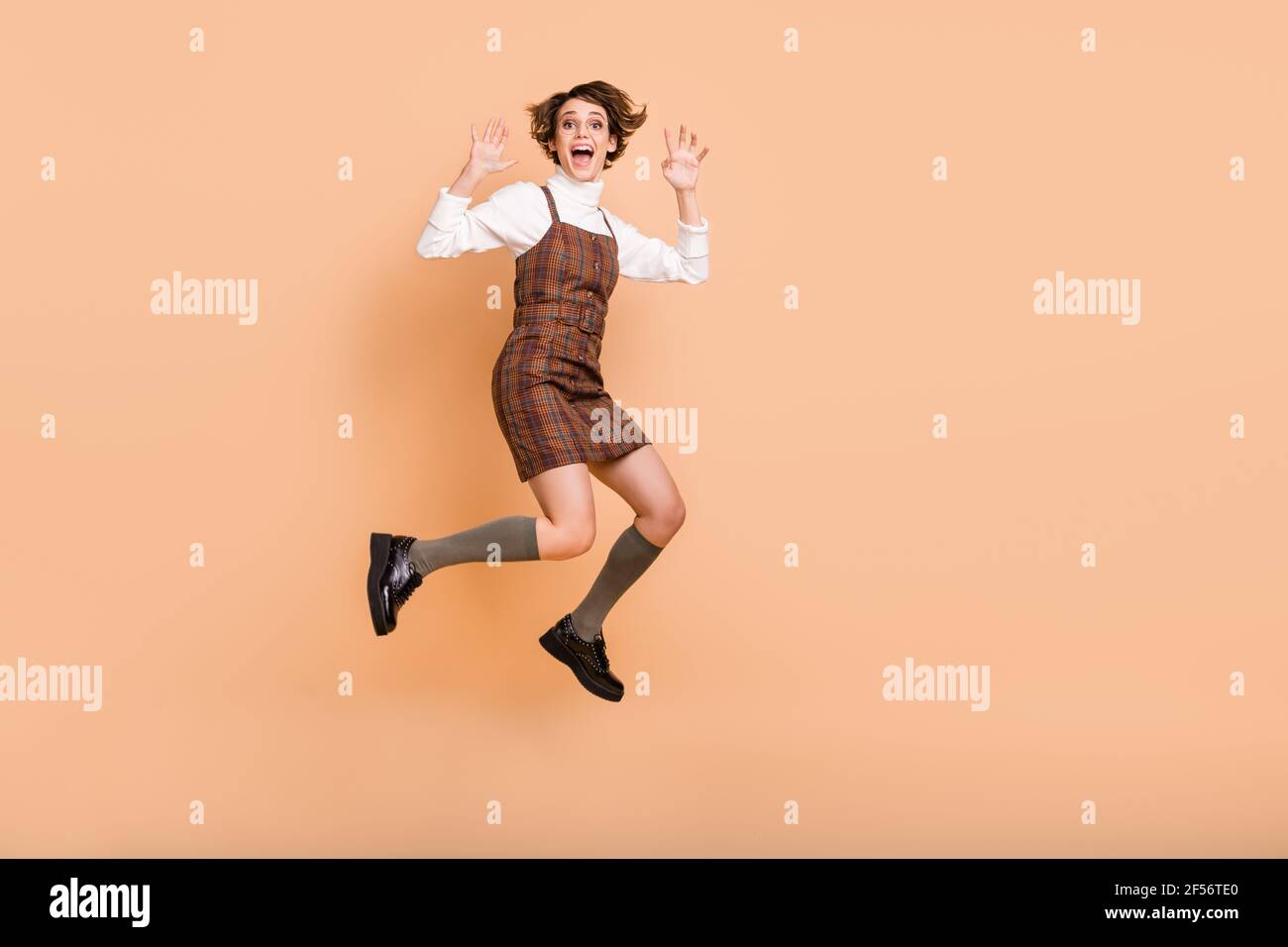 Full size profile photo of optimistic short hairdo girl jump run show cat wear dress socks shoes isolated on peach background Stock Photo