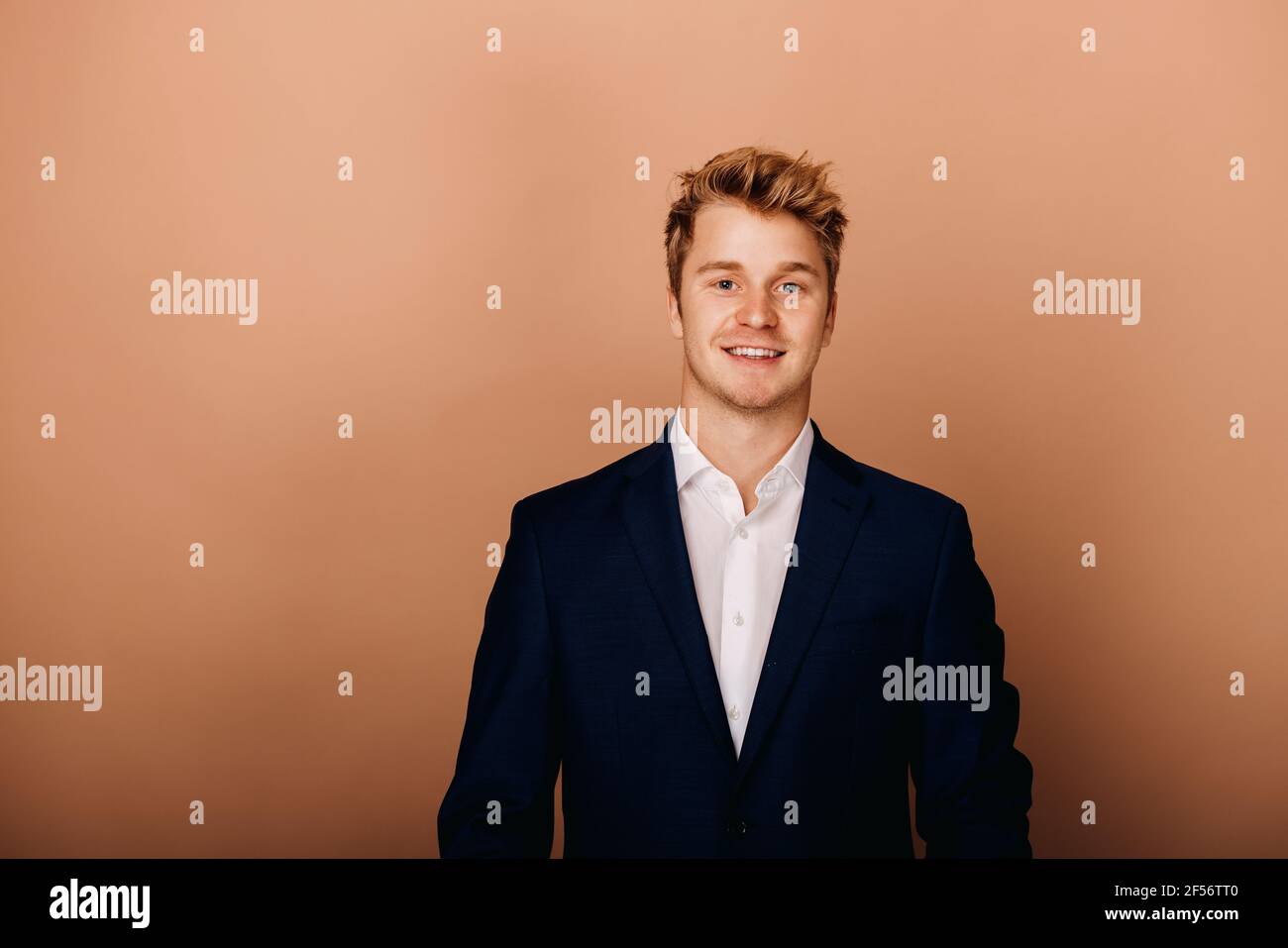Handsome businessman standing against brown background Stock Photo