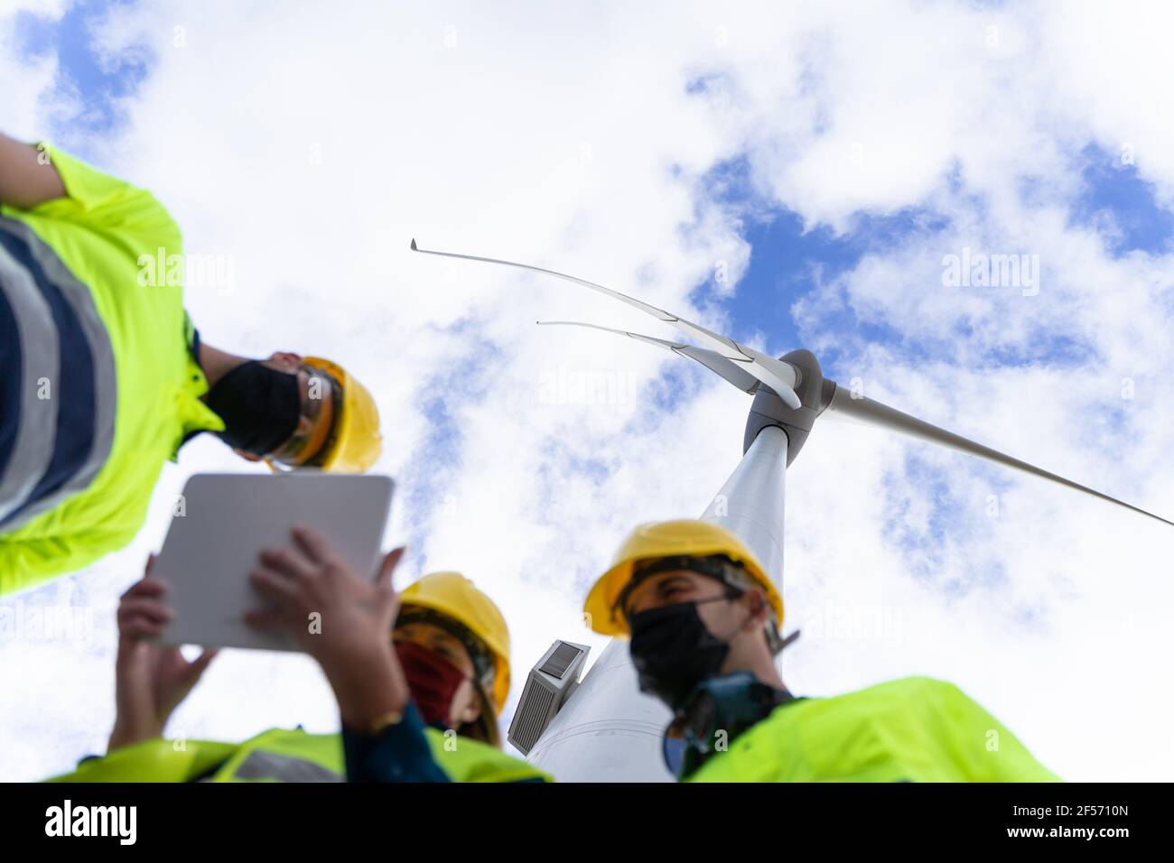 Engineer woman explaining being operated renewable energy with digital tablet. Concept of clean energy with wind turbines. Stock Photo