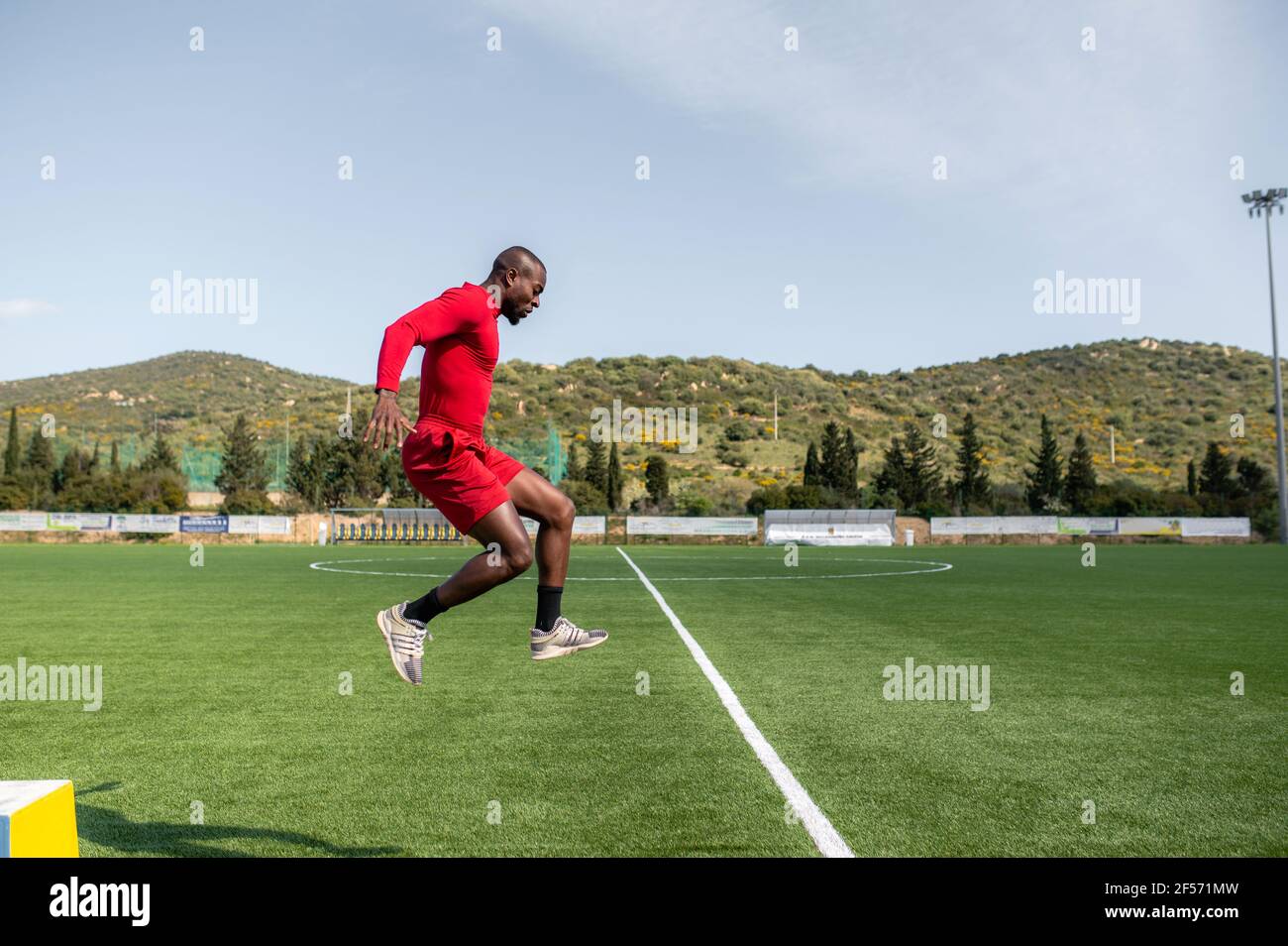 African black sportsman training in a football field jumping high. Stock Photo