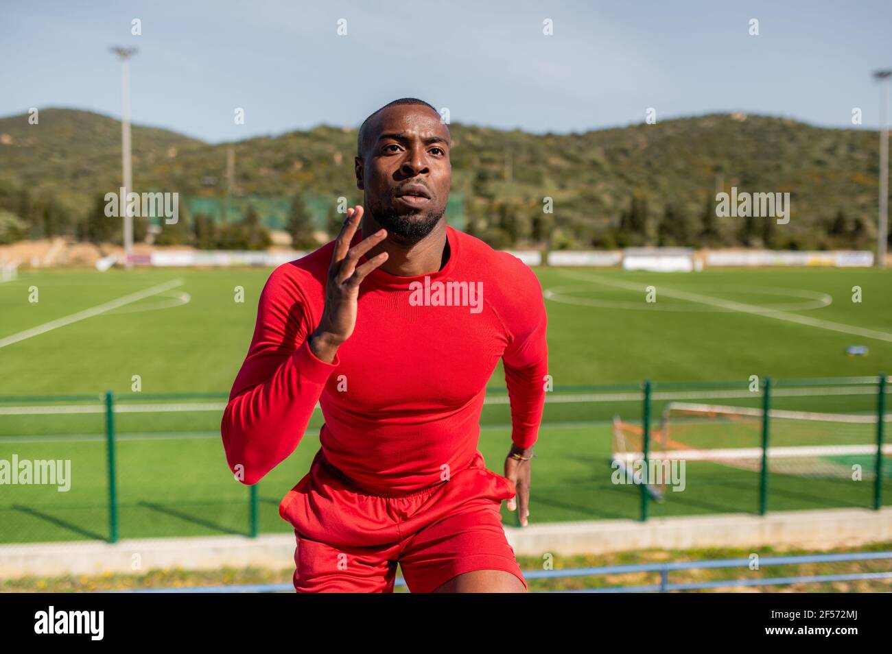 Black African sportsman running and training outdoors with field track on background. Stock Photo
