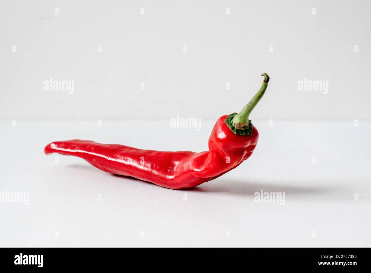An Organic Red Romano Pepper against a plain background Stock Photo