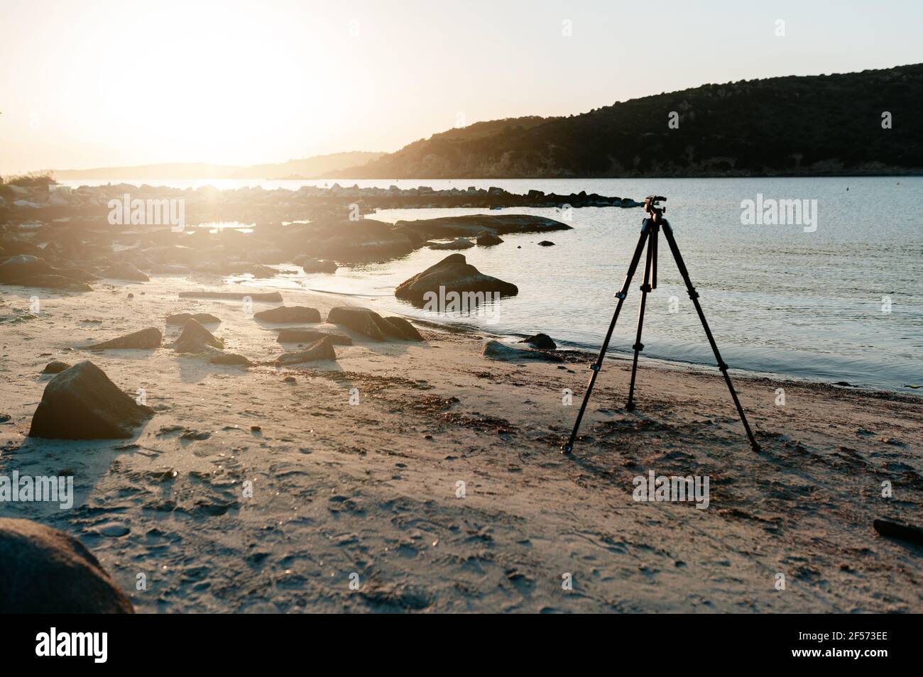 Silhouette of camera on tripod with sunset seascape colors on ...
