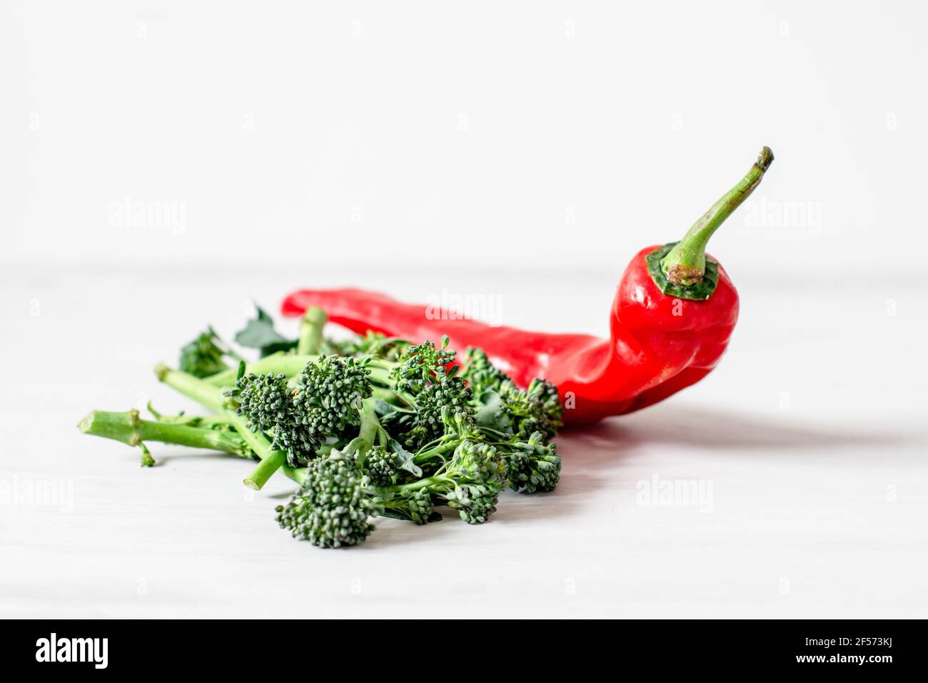 An Organic Red Romano Pepper with organic Tenderstem broccoli spears minimalist setting Stock Photo
