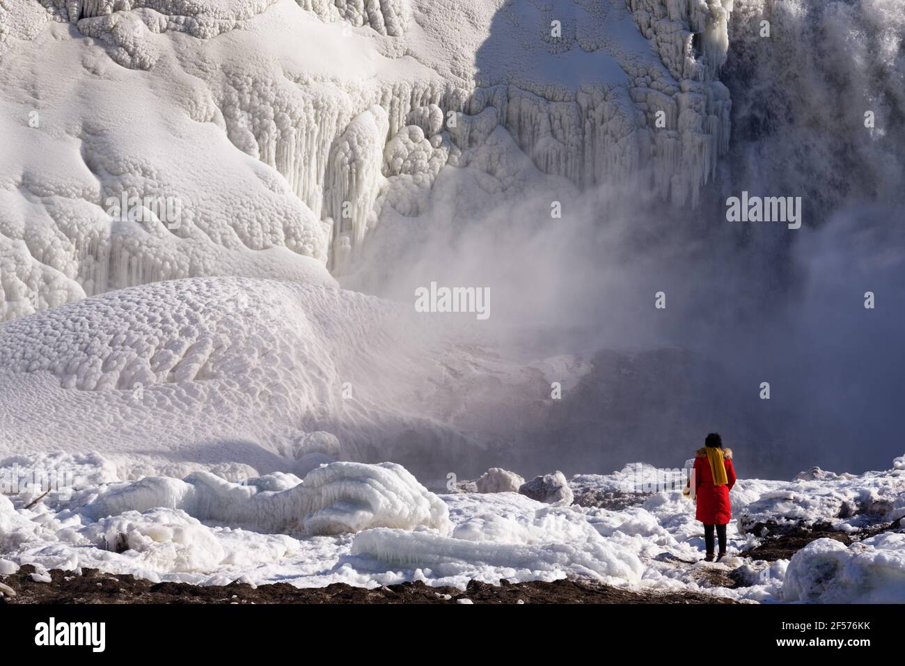 A lone lady in red looking at the frozen Chutes de la Chaudière in Quebec City, Canada Stock Photo