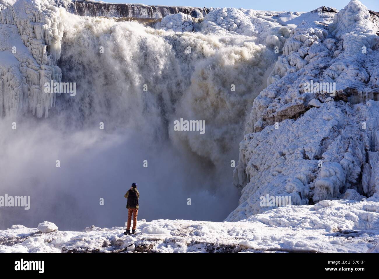 A lone man in red looking at the frozen Chutes de la Chaudière in Quebec City, Canada Stock Photo