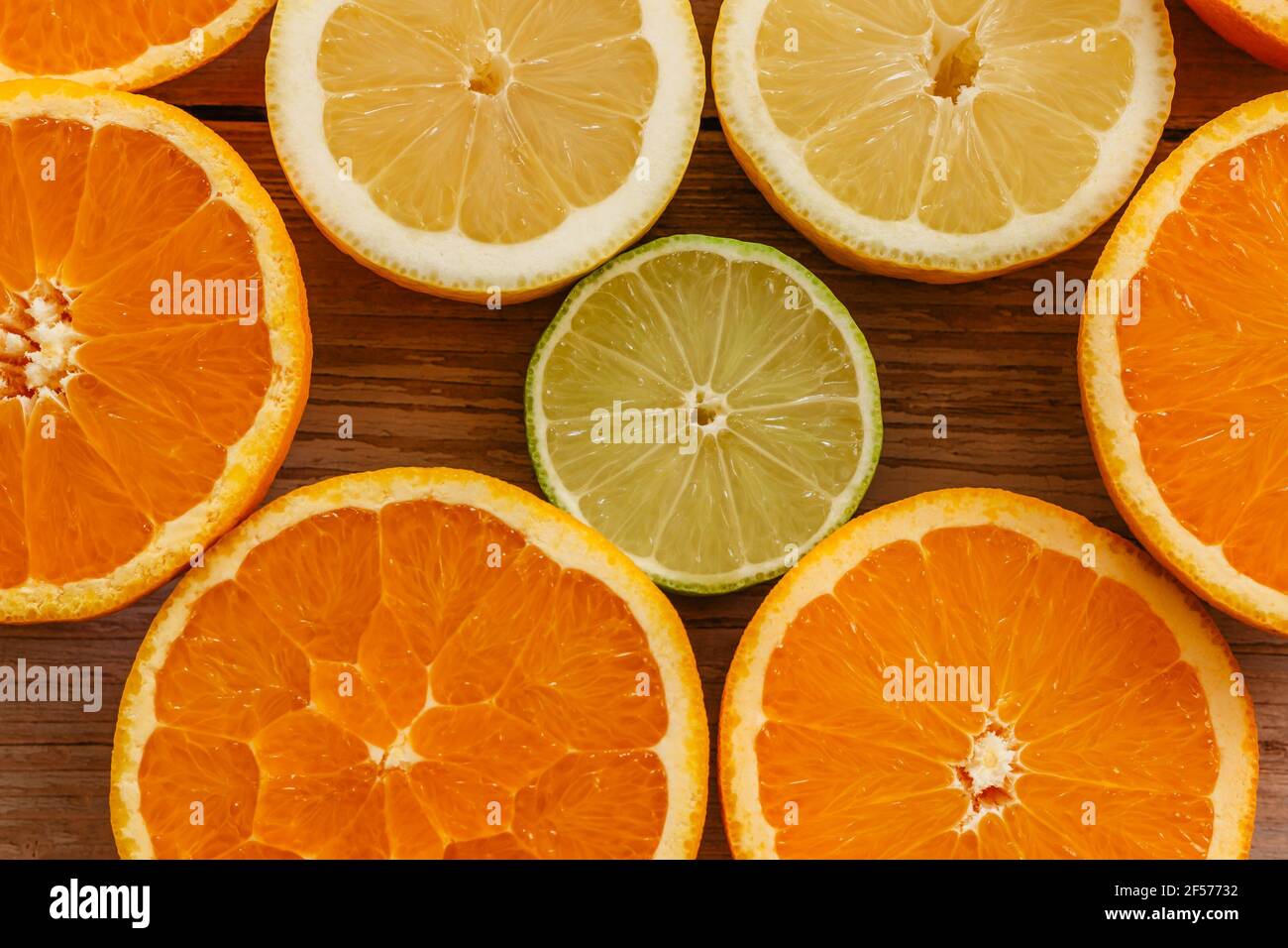 Oranges,limes and lemons slides on wooden table view from above.Beautiful background with fresh fruit half cut.Healthy eating vitamin C.Summer tropic Stock Photo